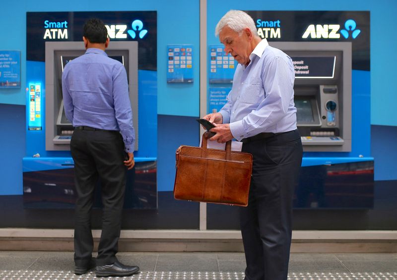 Customers stand next to automatic tellar machines located outside a branch of the Australia and New Zealand Banking Group (ANZ) in central Sydney