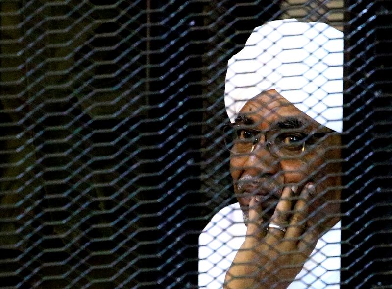 FILE PHOTO: Sudan's former president Omar Hassan al-Bashir sits inside a cage at the courthouse where he is facing corruption charges, in Khartoum