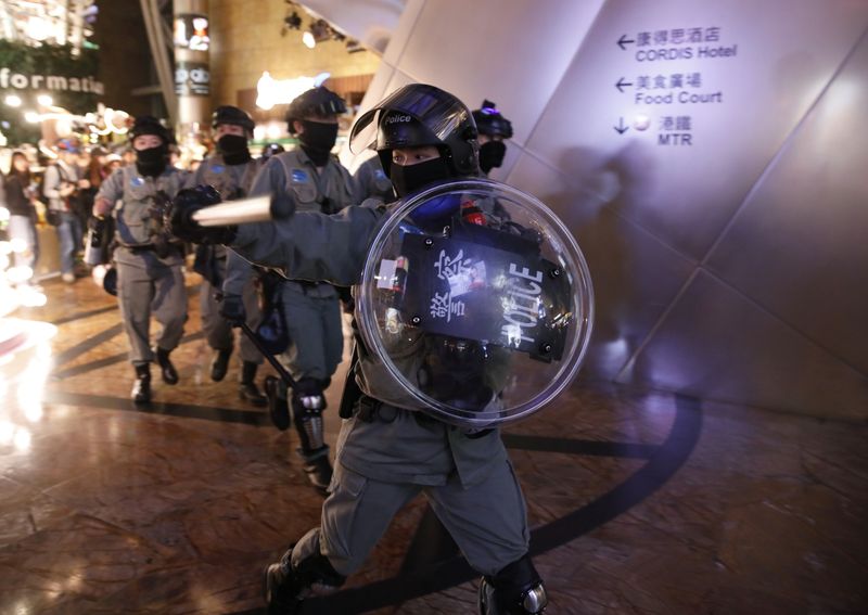 Riot police hold back anti-government protesters at a shopping mall in Hong Kong