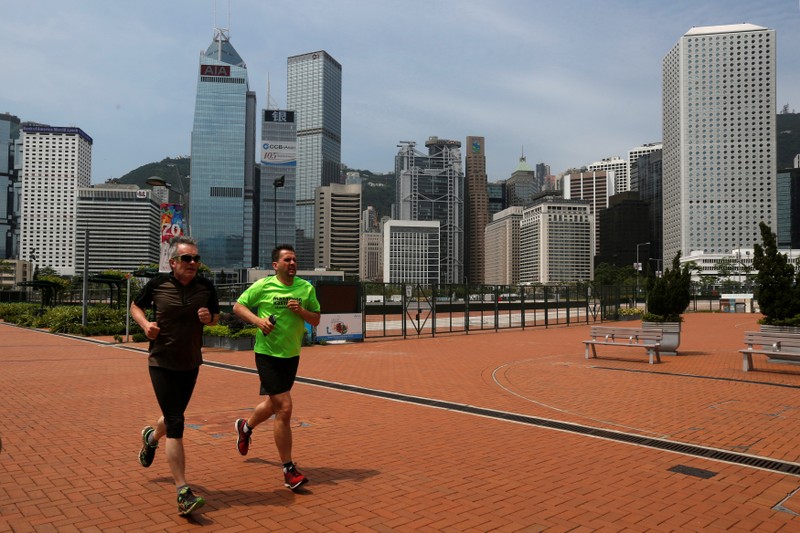 People jog in front of office towers at the financial Central district in Hong Kong