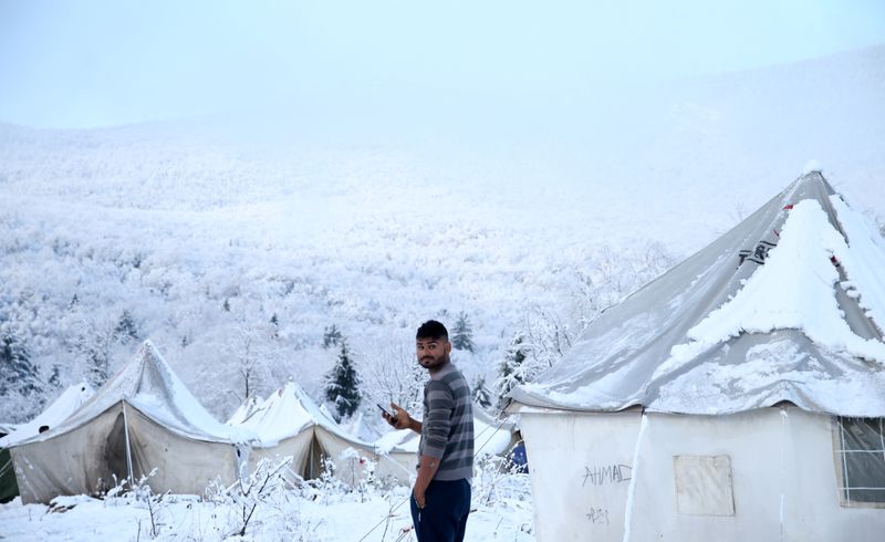 A migrant stands at a snow covered makeshift forest camp near the Croatian border in Bihac