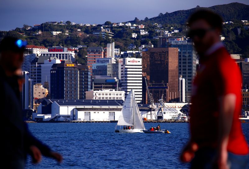 Pedestrians walk past a sailing boat as it passes in front of the central business district of Wellington in New Zealand