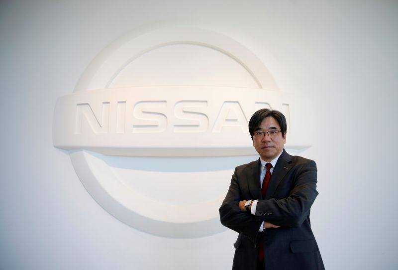 Nissan Executive Vice President Sakamoto poses with the carmaker's logo in the showroom at the carmaker's headquarters in Yokohama