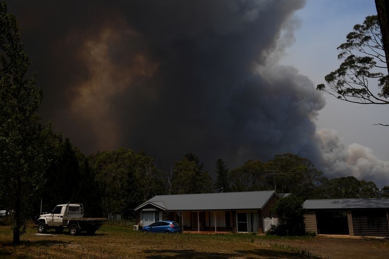 A home is seen as smoke from the Grose Valley Fire rises in the distance, at Bilpin, New South Wales