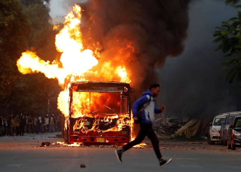 A man runs past a burning bus that was set on fire by demonstrators during a protest against a new citizenship law, in New Delhi