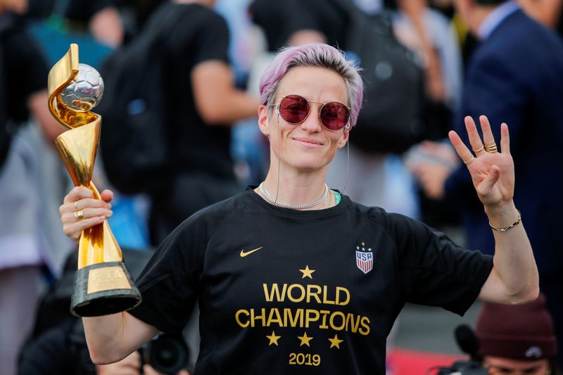 FILE PHOTO: Megan Rapinoe gestures the number 4 with her fingers as she holds the Trophy for the FIFA Women's World Cup while the U.S. team arrives at the Newark International Airport, in Newark
