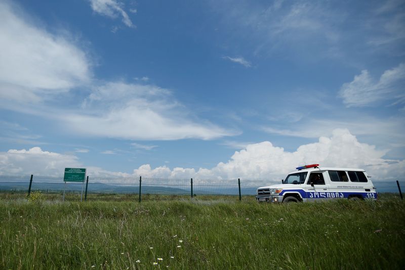 FILE PHOTO: A police car patrols along a border fence on the de facto border of Georgia's breakaway region of South Ossetia near Dvani