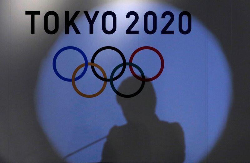 Shadow of of Tokyo governor Yuriko Koike is seen on the logo of Tokyo 2020 Olympic games during the Olympic and Paralympic flag-raising ceremony at Tokyo Metropolitan Government Building in Tokyo