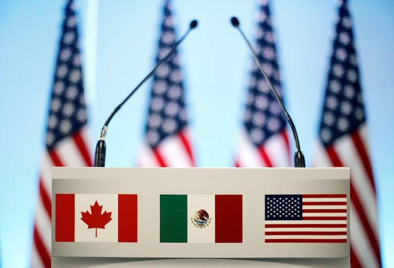 FILE PHOTO: The flags of Canada, Mexico and the U.S. are seen on a lectern before a joint news conference on the closing of the seventh round of NAFTA talks in Mexico City