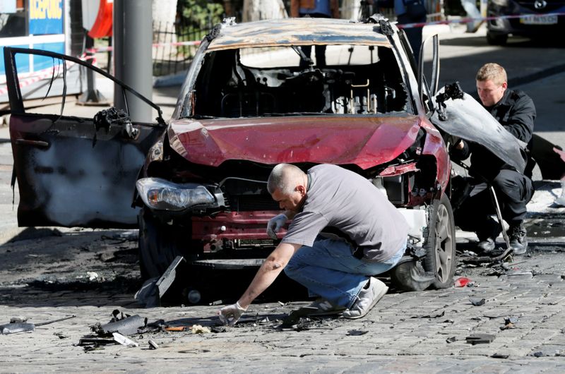 FILE PHOTO: Investigators inspect a damaged car at the site where journalist Pavel Sheremet was killed by a car bomb in central Kiev