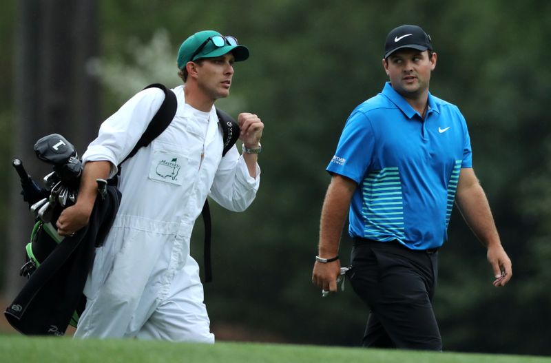 Reed of the U.S. talks with his caddie Karain as they walk off the 12th tee during third round play of the 2018 Masters golf tournament in Augusta