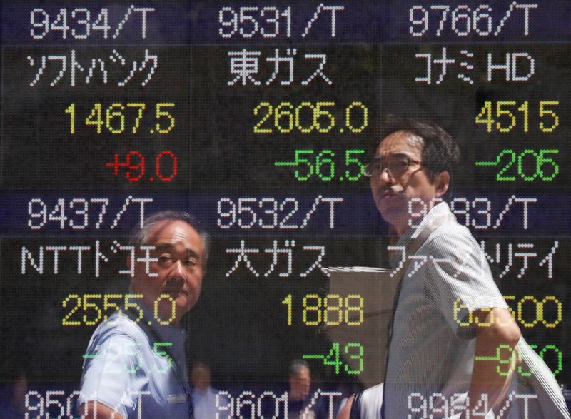 FILE PHOTO: Passersby are reflected on a stock quotation board outside a brokerage in Tokyo
