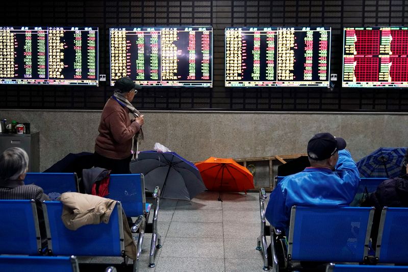 FILE PHOTO: Investors look at screens showing stock information at a brokerage house in Shanghai