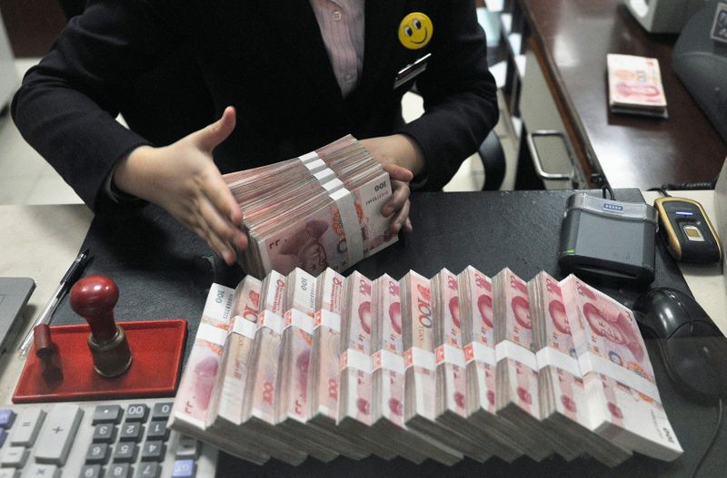 A clerk arranges bundles of 100 Chinese yuan banknotes at a branch of China Merchants Bank in Hefei