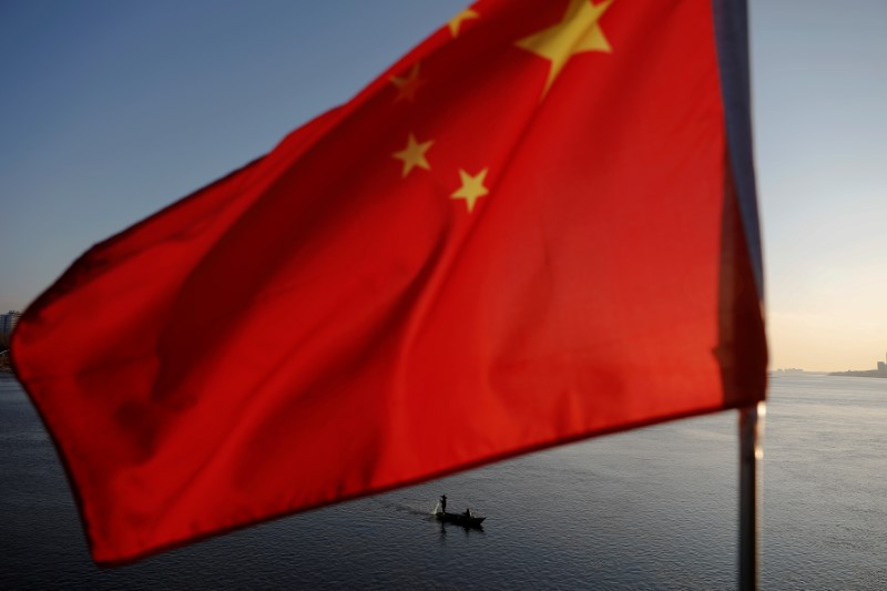 FILE PHOTO: North Korean fishermen are seen as a Chinese flag flutters from the Broken Bridge