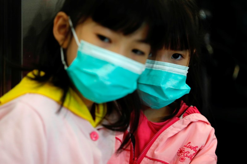 Children wear masks to prevent an outbreak of a new coronavirus at the Hong Kong West Kowloon High Speed Train Station, in Hong Kong