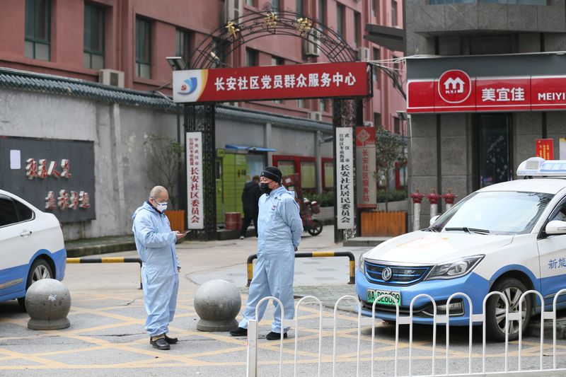 Taxi drivers in protective suits are seen in front of a residential area, following an outbreak of the new coronavirus and the city’s lockdown, in Wuhan
