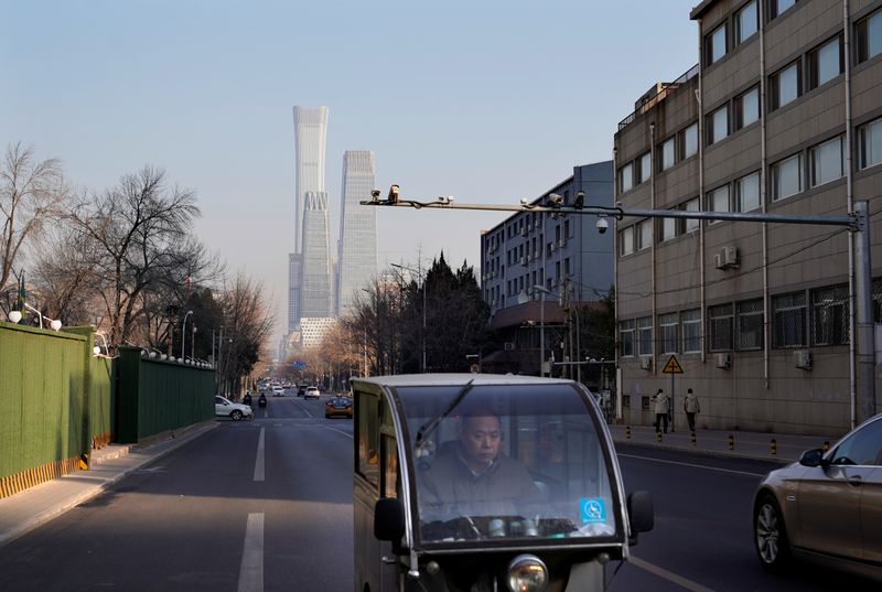 A man rides a motor tricycle past the buildings of Beijing's central business area