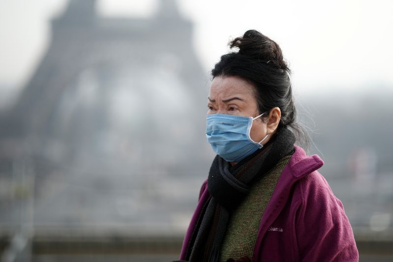 A woman wears a face mask on the Trocadero esplanade in front of the Eiffel Tower in Paris