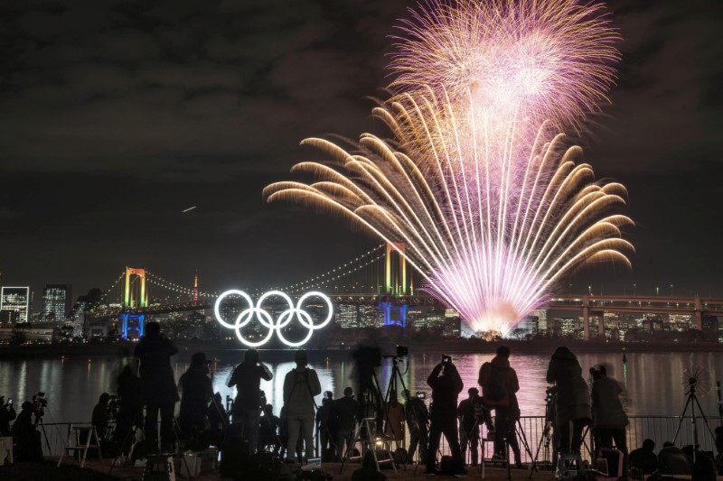 Fireworks light up the sky near the illuminated Olympic rings at a ceremony to mark six months before the start of the 2020 Olympic Games in Tokyo