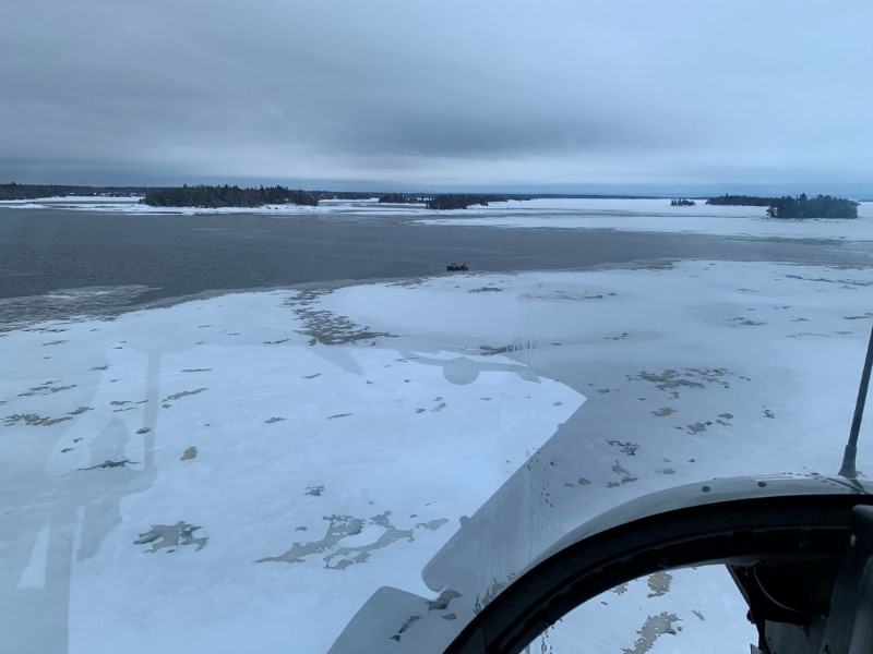A helicopter carrying provincial police officers from the Surete du Quebec searches an area for five missing French snowmobilers off Beemer Island