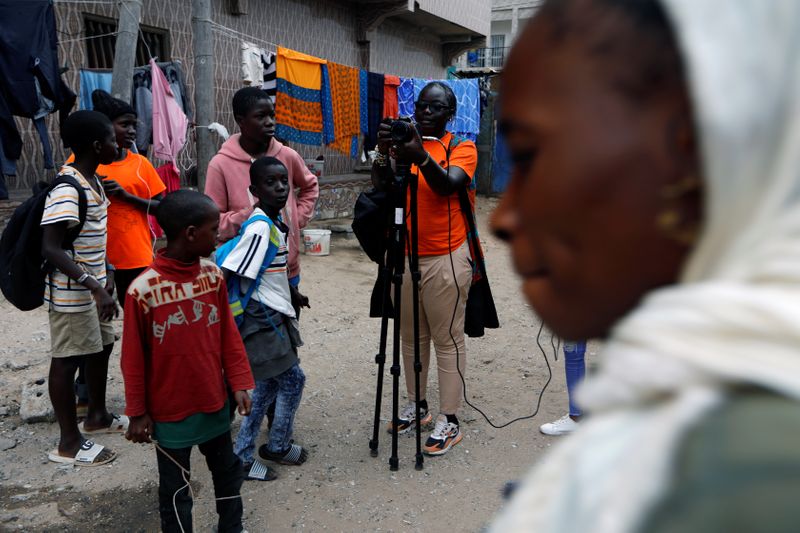 Fatou Warkha, 30, an activist who founded the community web TV Warkhatv.com, shoots footage in the streets of Pikine, on the outskirts of Dakar
