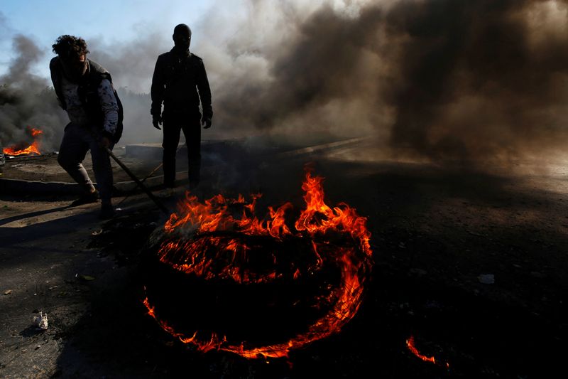Iraqi demonstrators burn tires to block a road during ongoing anti-government protests in Najaf