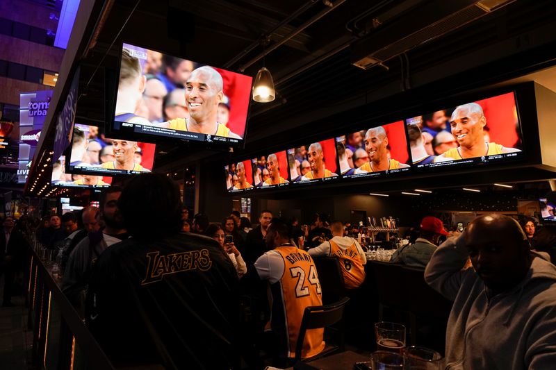 Fans of NBA basketball star Kobe Bryant watch a replay of his last NBA game as they sit at an outdoor bar near the Staples Center at L.A. Live in Los Angeles,