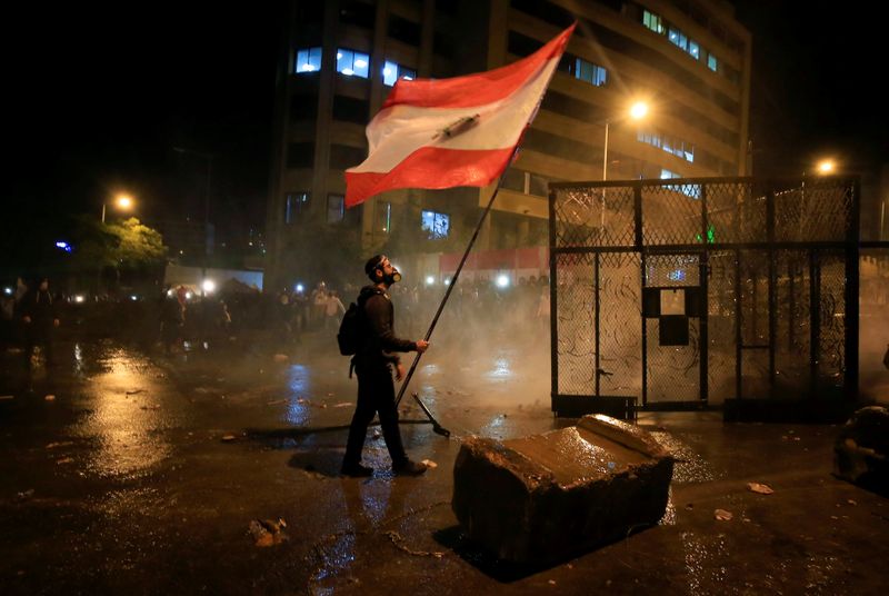 A demonstrator holds the Lebanese flag during a protest against the newly formed government outside the government headquarters in downtown Beirut