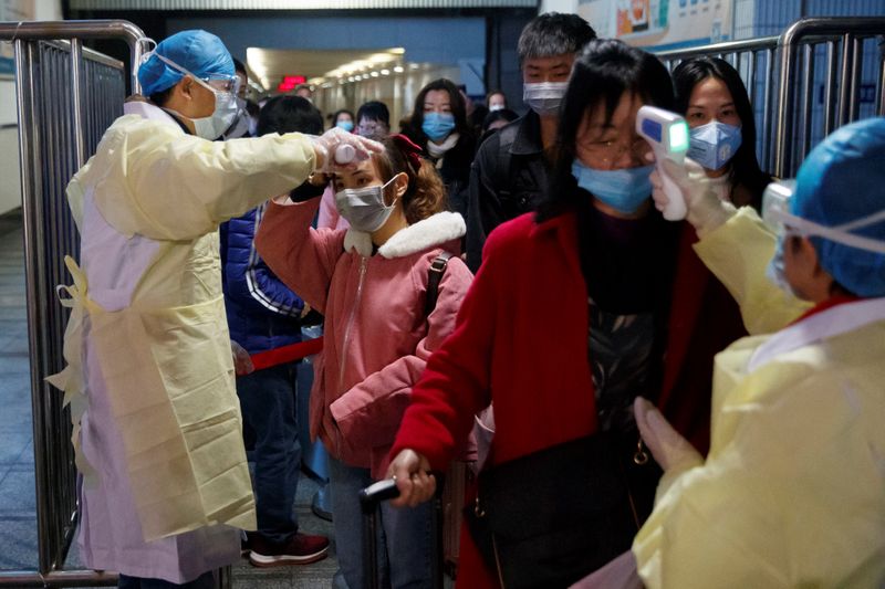 Medical workers take the temperature of passengers after they got off the train in Jiujiang