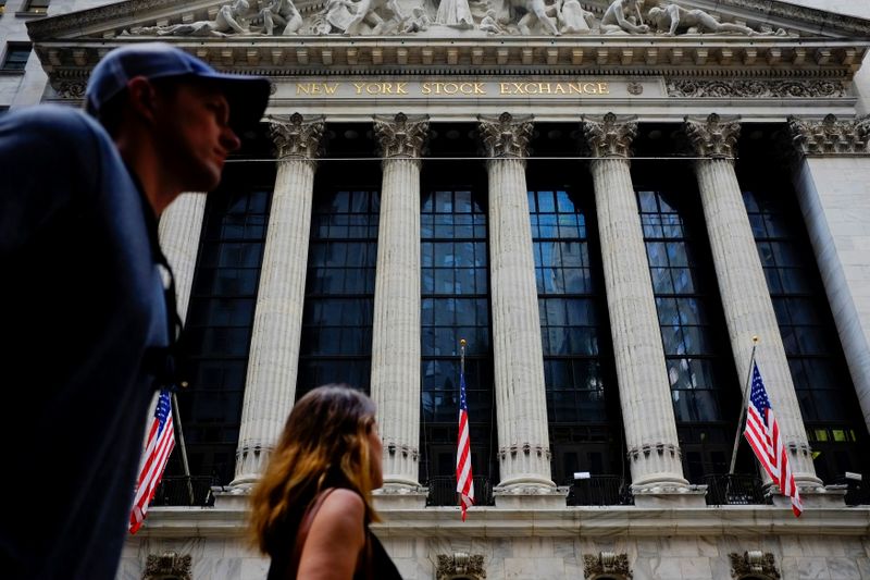 People walk by New York Stock Exchange in the financial district in New York