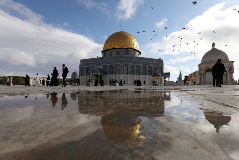 FILE PHOTO: People walking near the Al-Aqsa mosque reflect in a puddle next to a gate to the compound known to Jews as Temple Mount and to Muslims as The Noble Sanctuary, in Jerusalem's Old City