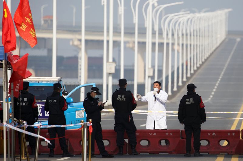 A man who arrived from Hubei province talks with police at a checkpoint at the Jiujiang Yangtze River Bridge as the country is hit by an outbreak of the novel coronavirus in Jiujiang