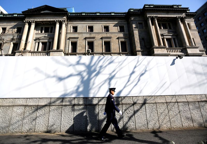 FILE PHOTO: A security guard walks past the front of the Bank of Japan headquarters in Tokyo