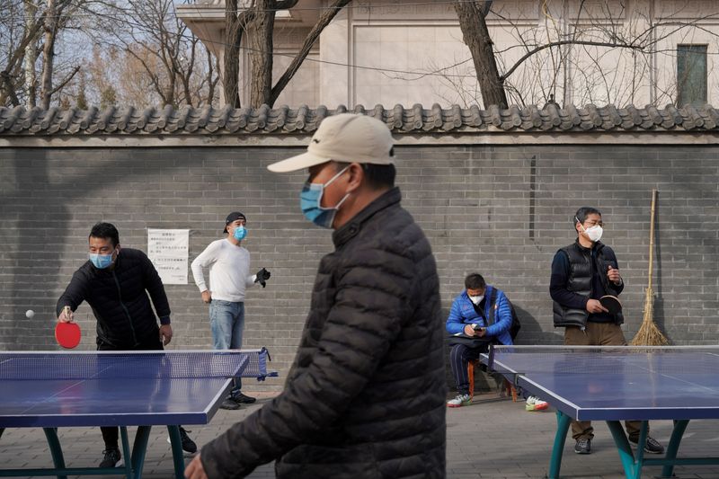 People wearing face masks play table tennis at a park, following an outbreak of the novel coronavirus in the country, in Beijing