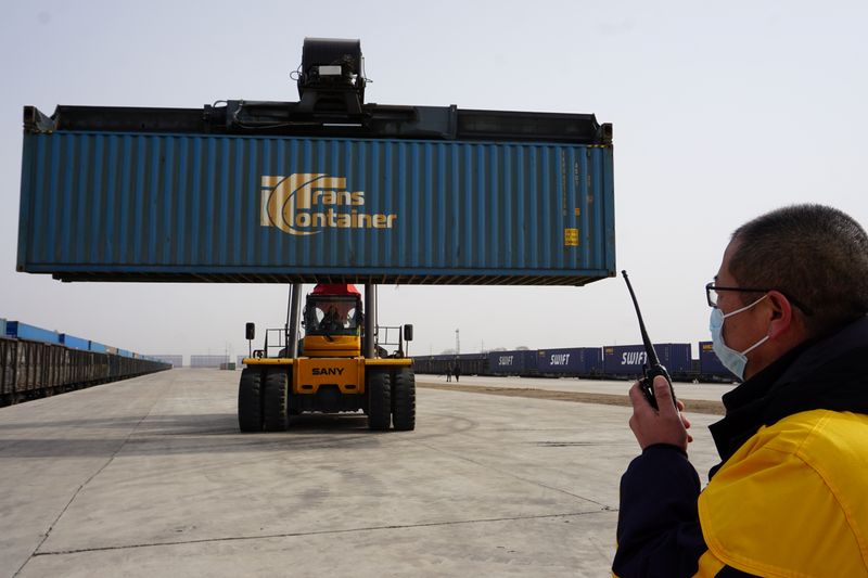 Workers transport a container from a China-Europe freight train that departed from Russia's Omsk, at a cargo terminal in Ulanqab
