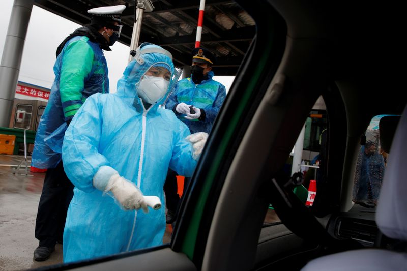 A medical worker checks a driver's temperature at a checkpoint as the country is hit by an outbreak of the novel coronavirus in Susong County