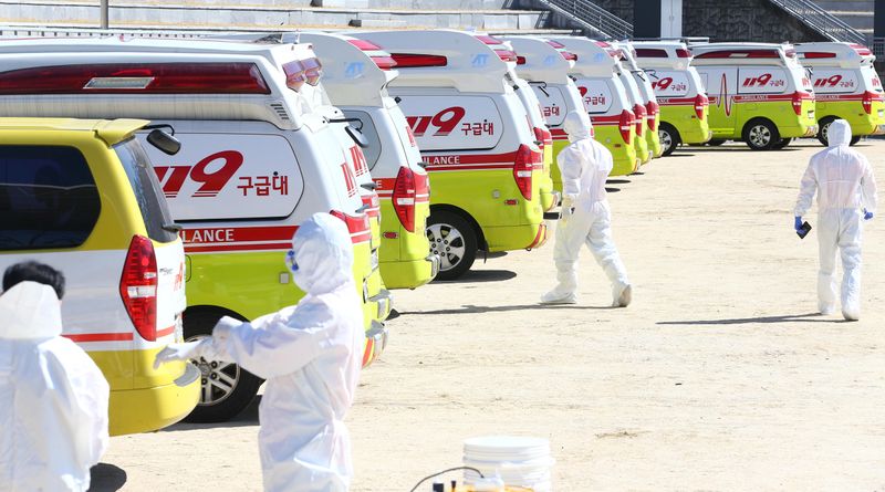 Medical workers get ready as ambulances are parked to transport a confirmed coronavirus patient in Daegu