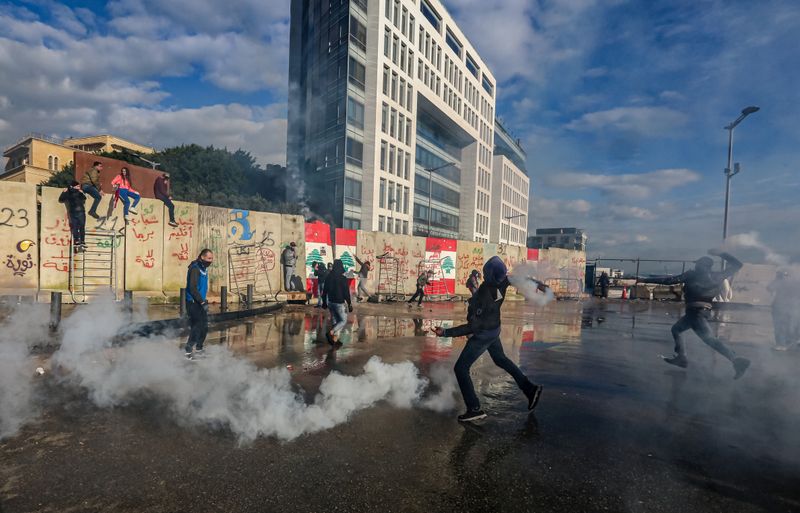 A protestor throws back a tear gas canister during a protest seeking to prevent MPs and government officials from reaching the parliament for a vote of confidence, in Beirut