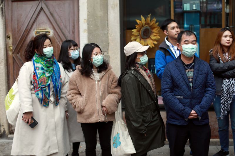 People wear protective masks at Venice Carnival, which the last two days of, as well as Sunday night's festivities, have been cancelled because of an outbreak of coronavirus, in Venice