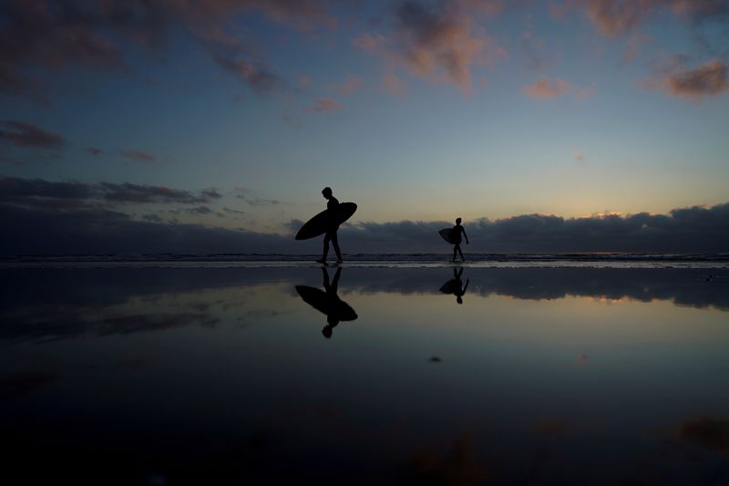 FILE PHOTO: A father and his son make their way in from surfing at Cardiff State Beach in Encinitas