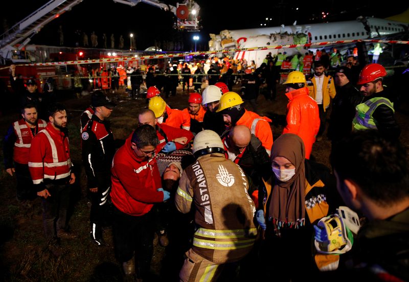 An injured person is carried away from Pegasus Airlines Boeing 737-86J plane, after it overran the runway during landing and crashed, at Istanbul's Sabiha Gokcen airport