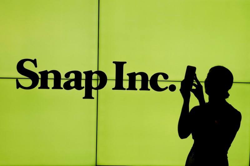 FILE PHOTO: A woman stands in front of the logo of Snap Inc. on the floor of the New York Stock Exchange in New York City