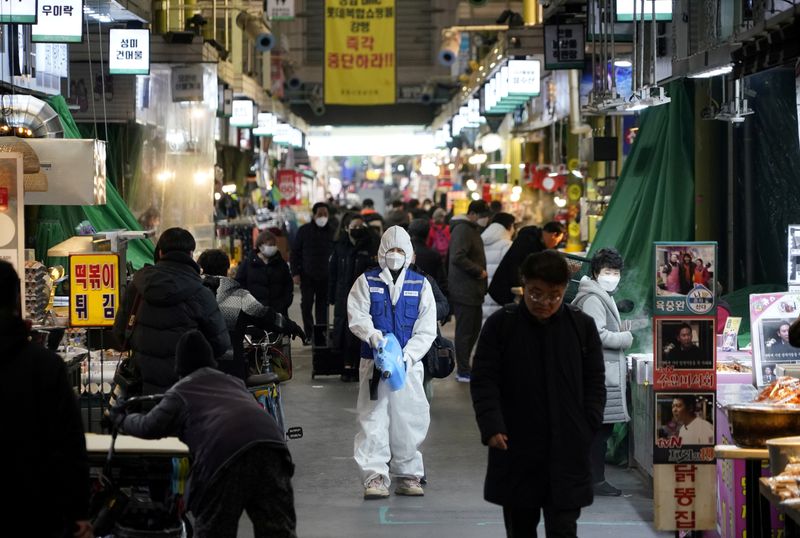 An employee from a disinfection service company sanitizes the floor of a traditional market in Seoul