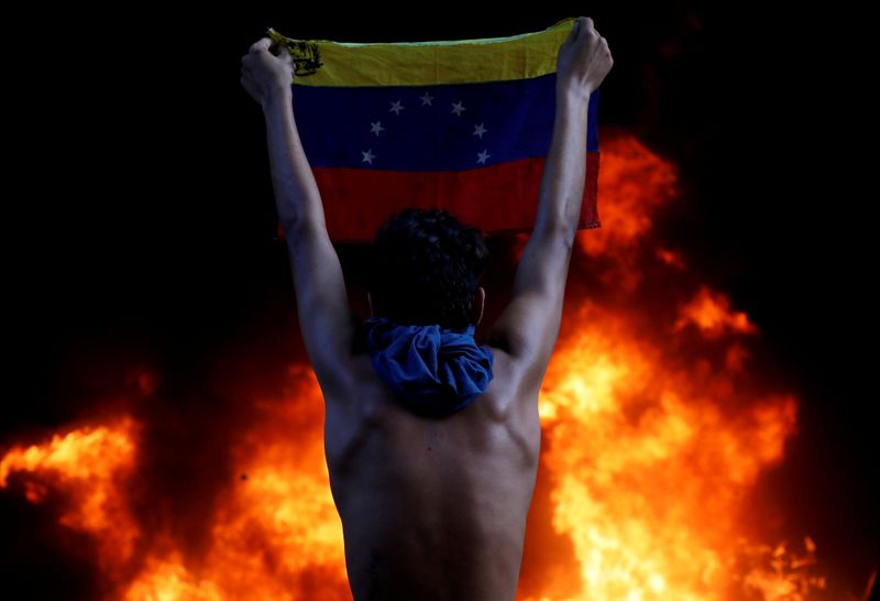 FILE PHOTO: A protester holds a national flag during a rally against Venezuela's President Nicolas Maduro in Caracas