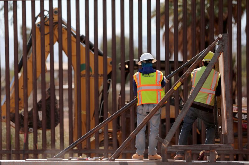 FILE PHOTO: Construction workers raise 30-foot high bollard style wall at US-Mexico border to replace a section near Calexico