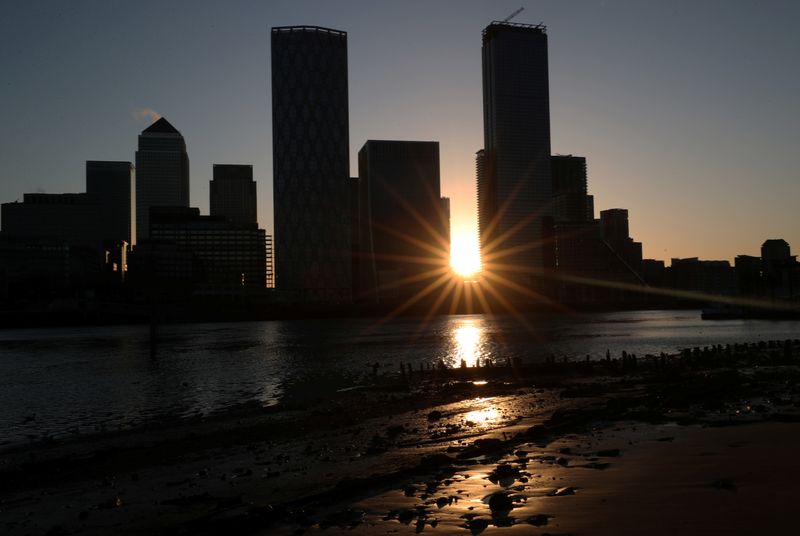 The sun rises behind the Canary Wharf financial district in London