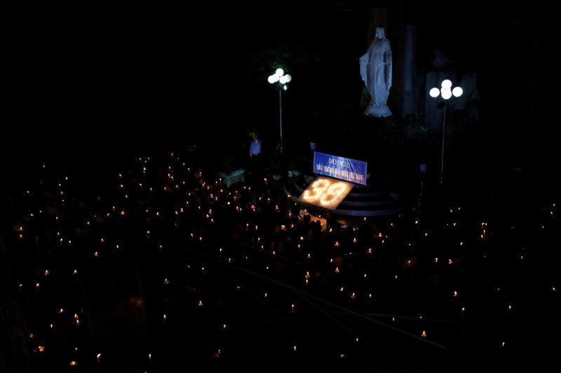 FILE PHOTO: Catholic believers hold lit candles during a mass prayer for 39 Vietnamese people found dead in a truck near London last month, at a church in Nghe An province