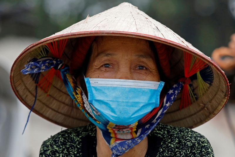 A woman wearing a protective mask walks in a village in Vinh Phuc province