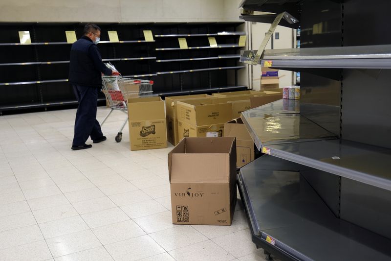 FILE PHOTO: A customer wears a mask as he walks past empty toilet paper shelves at a supermarket, following the outbreak of a new coronavirus, in Hong Kong